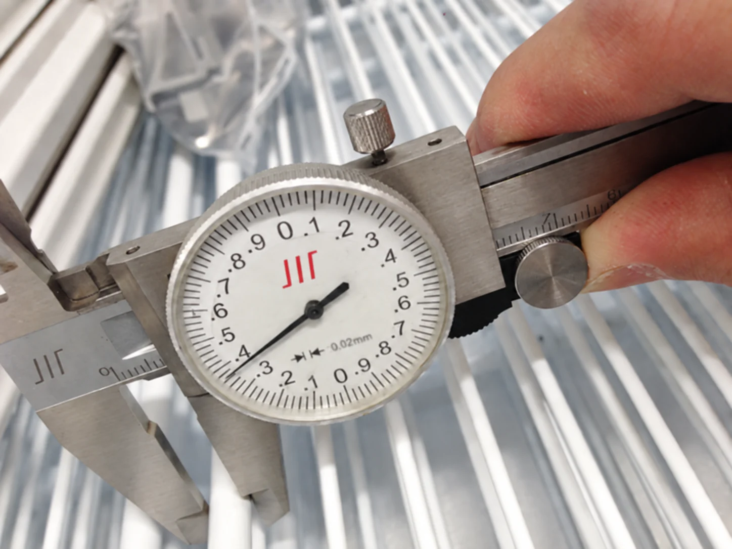 Dial caliper positioned around a metal shelf member for a diameter check